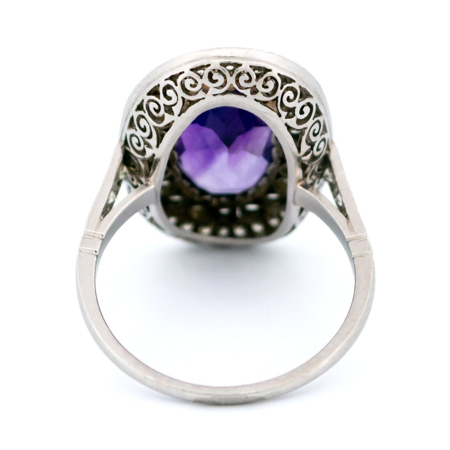 An oval shaped cluster ring with an amethyst centre and diamond surround, in platinum