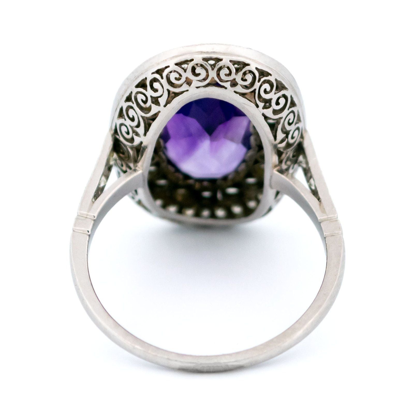 An oval shaped cluster ring with an amethyst centre and diamond surround, in platinum
