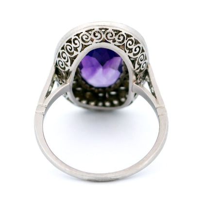 An oval shaped cluster ring with an amethyst centre and diamond surround, in platinum