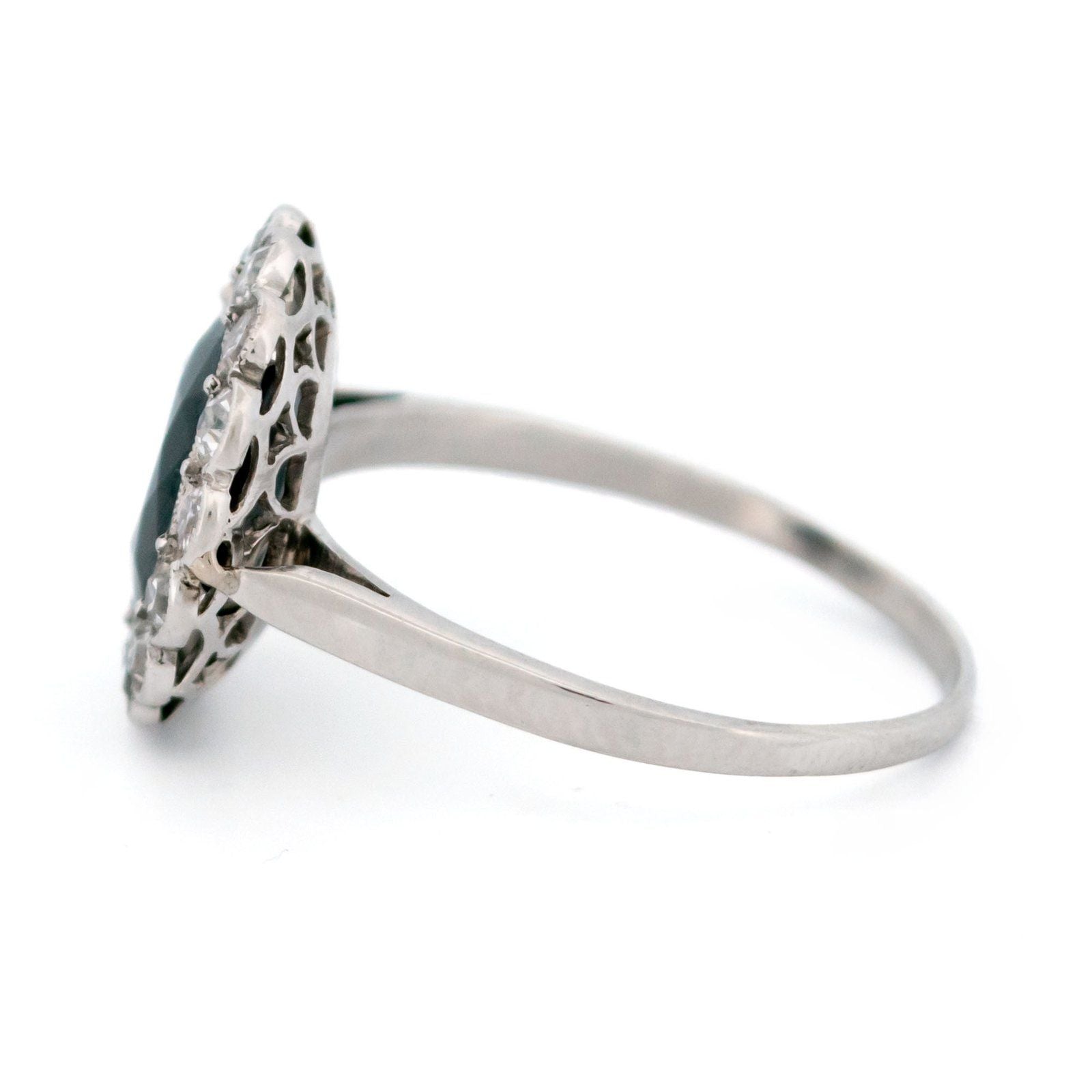A flower shaped cluster ring set with a central sapphire surrounded by a halo of round diamonds, in platinum