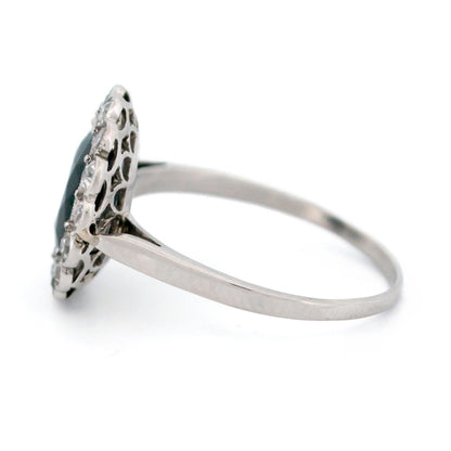 A flower shaped cluster ring set with a central sapphire surrounded by a halo of round diamonds, in platinum