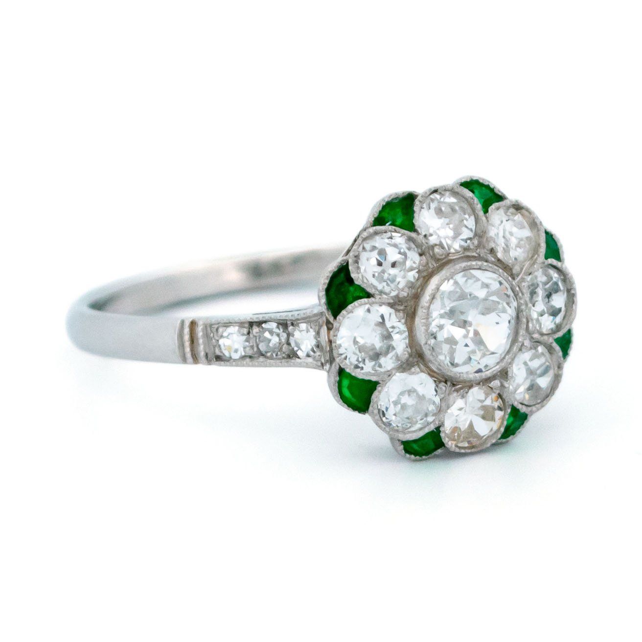 A diamond and emerald daisy cluster ring in platinum