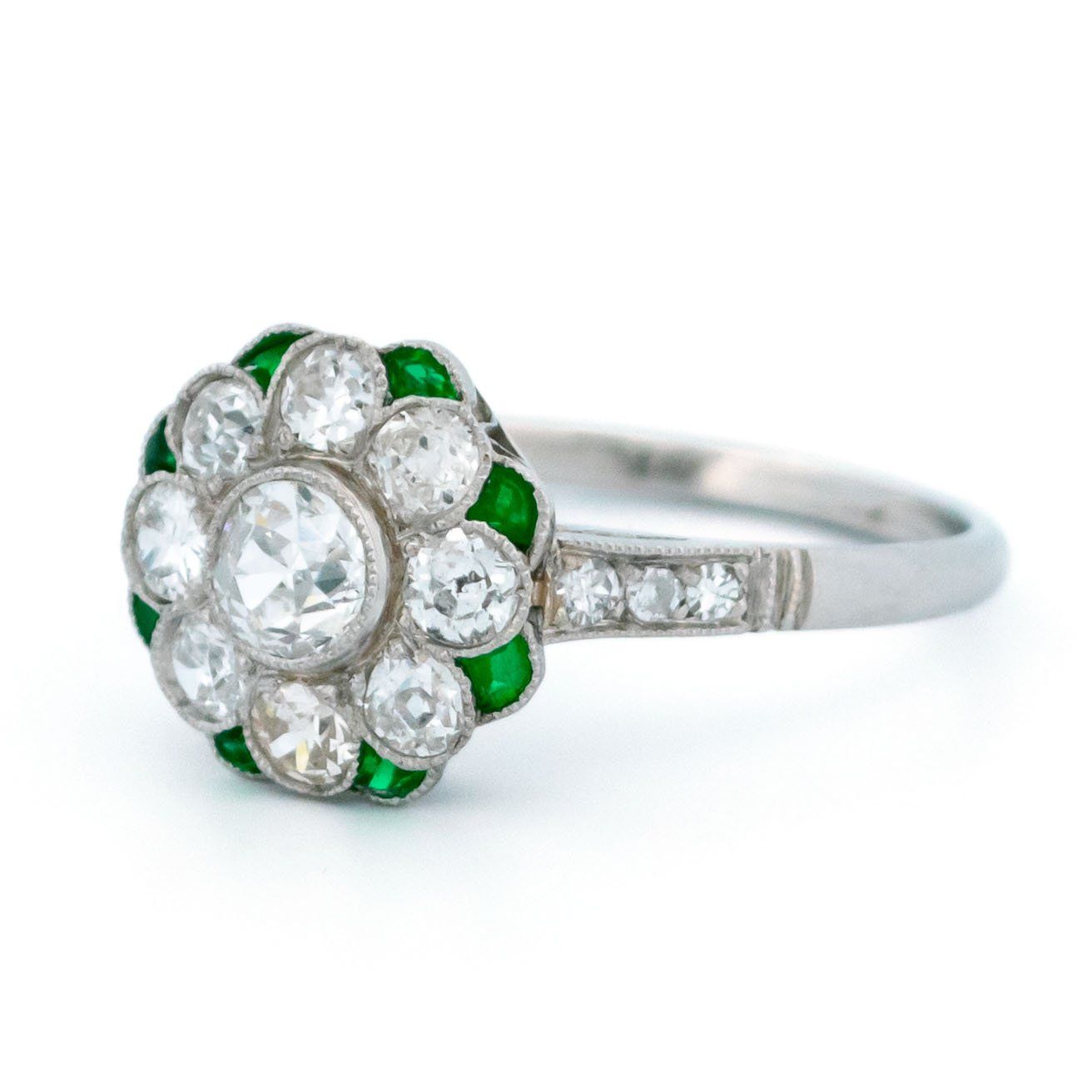 A diamond and emerald daisy cluster ring in platinum