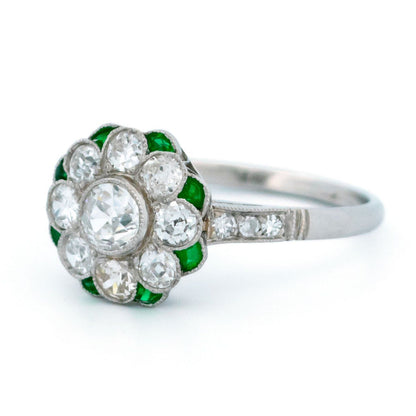 A diamond and emerald daisy cluster ring in platinum