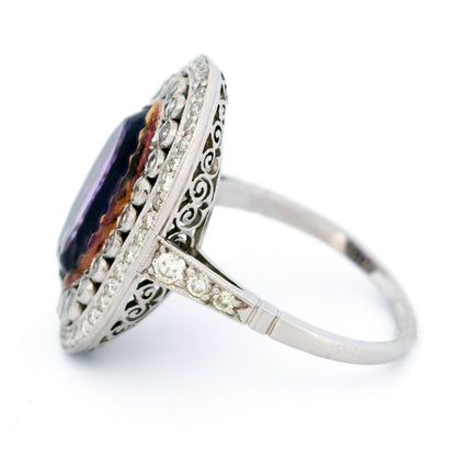 An oval shaped cluster ring with an amethyst centre and diamond surround, in platinum