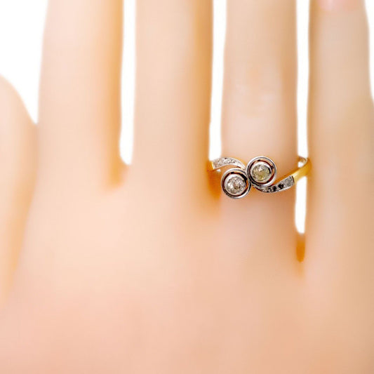 A two stone diamond crossover ring in yellow and white gold, modelled on a plastic hand