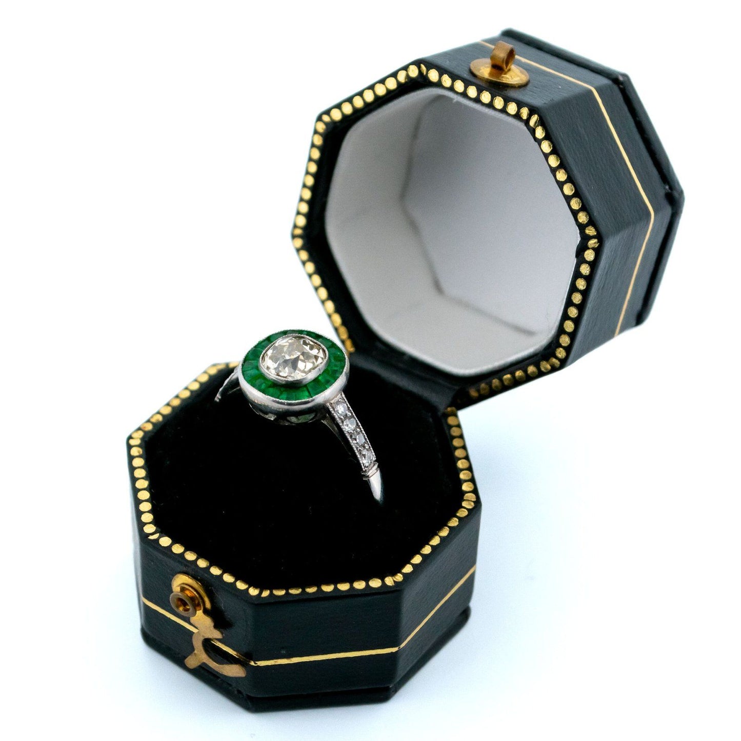 An emerald and diamond halo target cluster ring in platinum, in a ring box