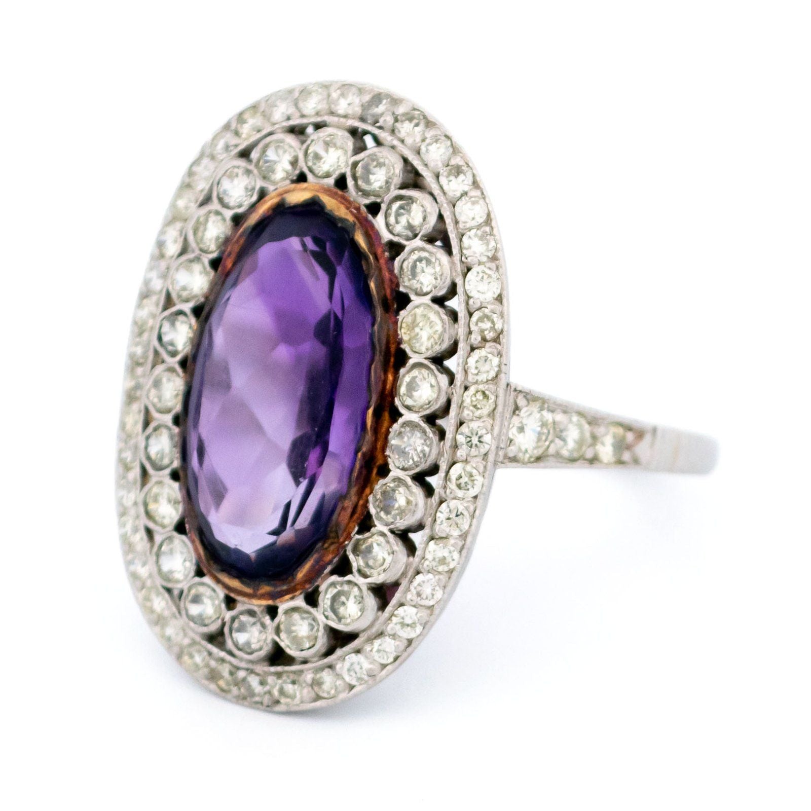 An oval shaped cluster ring with an amethyst centre and diamond surround, in platinum