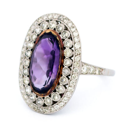 An oval shaped cluster ring with an amethyst centre and diamond surround, in platinum