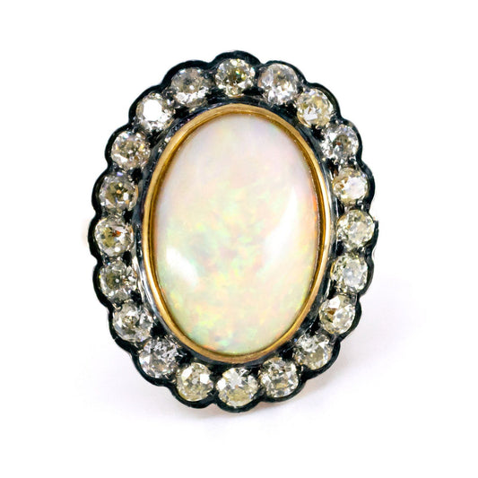 An oval shaped cluster ring with a central opal surrounded by diamonds, in gold and silver
