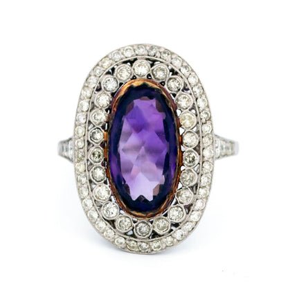 An oval shaped cluster ring with an amethyst centre and diamond surround, in platinum