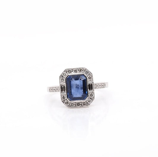 An emerald cut sapphire and diamond cluster ring in white gold