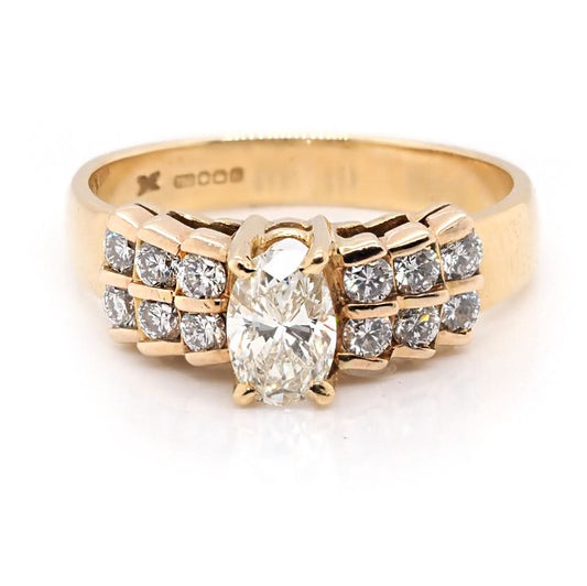 A yellow gold ring with a central oval cut diamond and brilliant cut diamond shoulders
