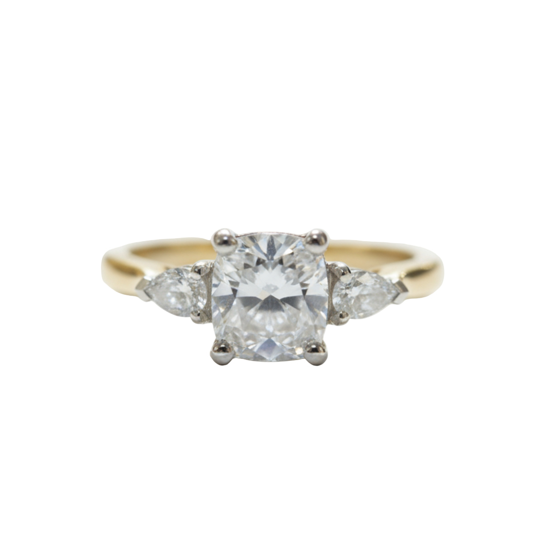 A three stone cushion cut and pear cut diamond ring in yellow and white gold