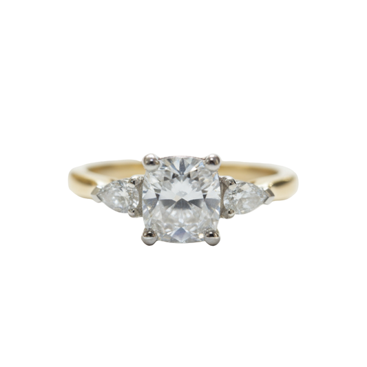 A three stone cushion cut and pear cut diamond ring in yellow and white gold