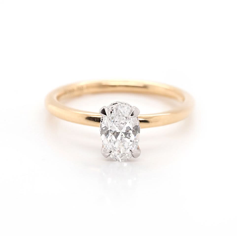 An oval diamond solitaire ring in yellow and white gold