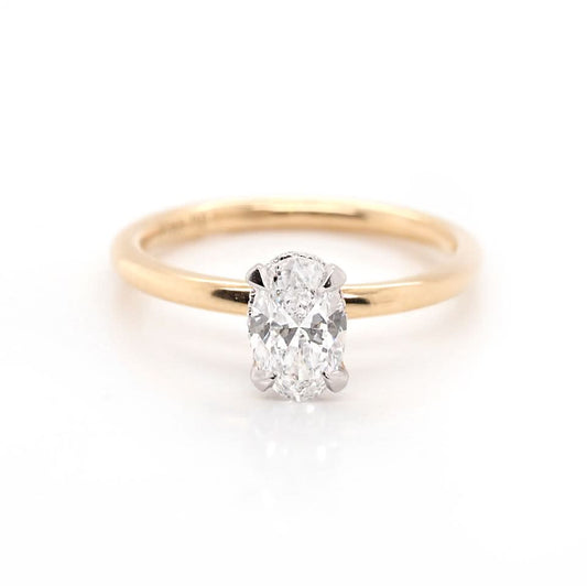 An oval diamond solitaire ring in yellow and white gold