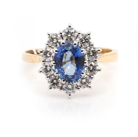 An oval sapphire and brilliant cut diamond cluster ring in yellow and white gold