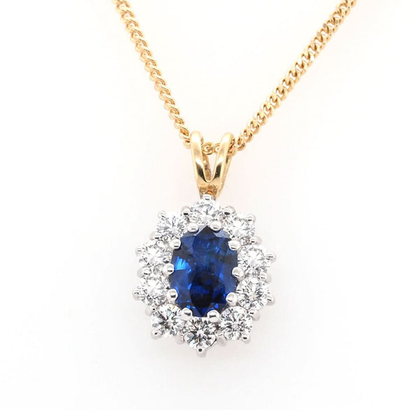 An oval cluster pendant with an oval sapphire and a diamond surround, in yellow and white gold, with a yellow gold chain