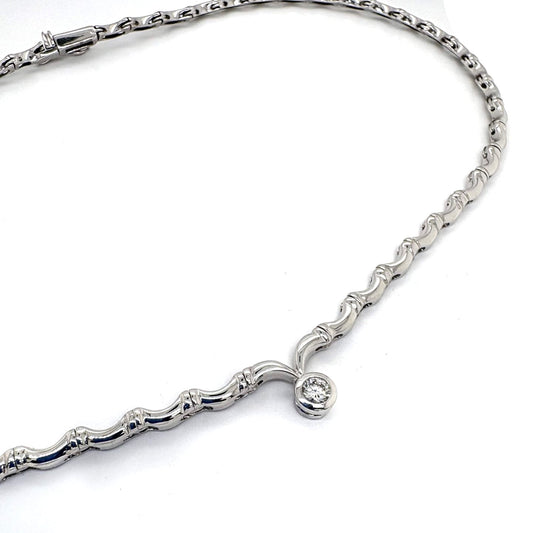 A white gold collar necklace with a diamond pendant drop