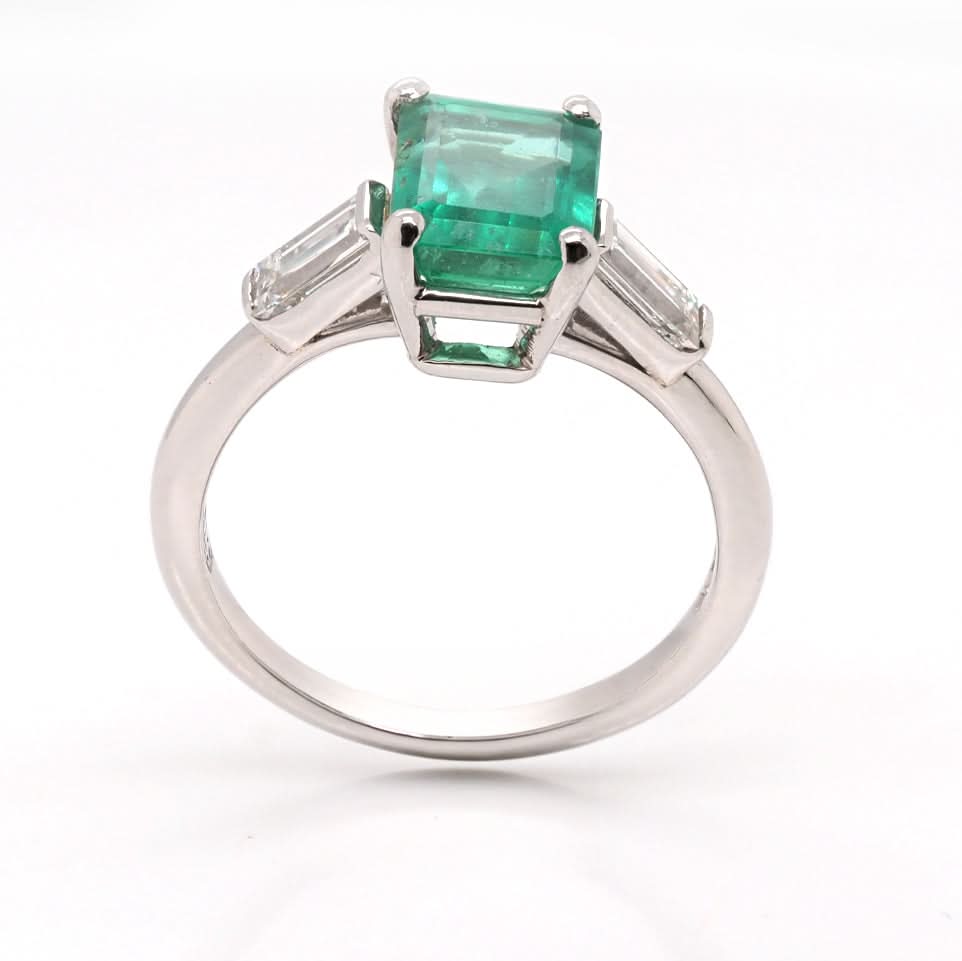 A three stone emerald and diamond ring in platinum