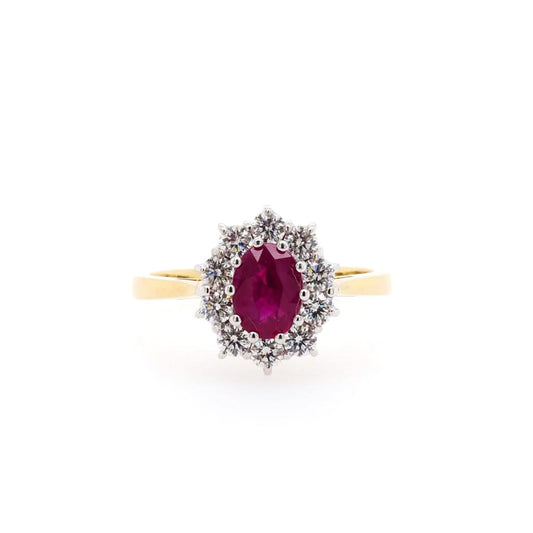 An oval shaped cluster ring with an oval ruby and round diamond surround, on a yellow gold shank