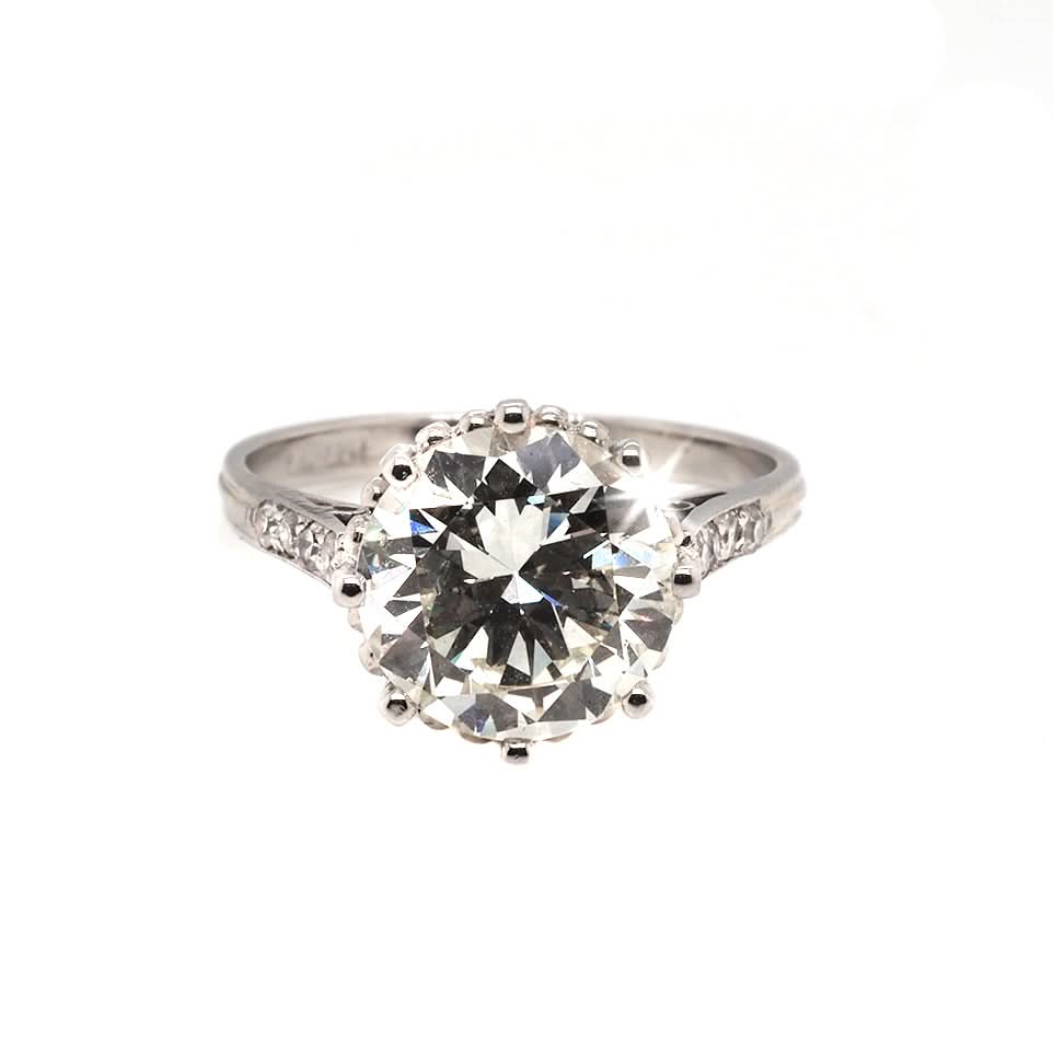 A single stone diamond engagement ring with diamond set shoulders mounted in platinum