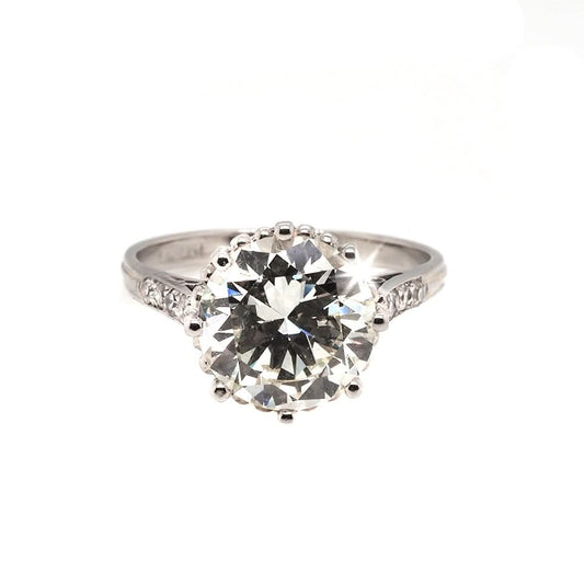A single stone diamond engagement ring with diamond set shoulders mounted in platinum
