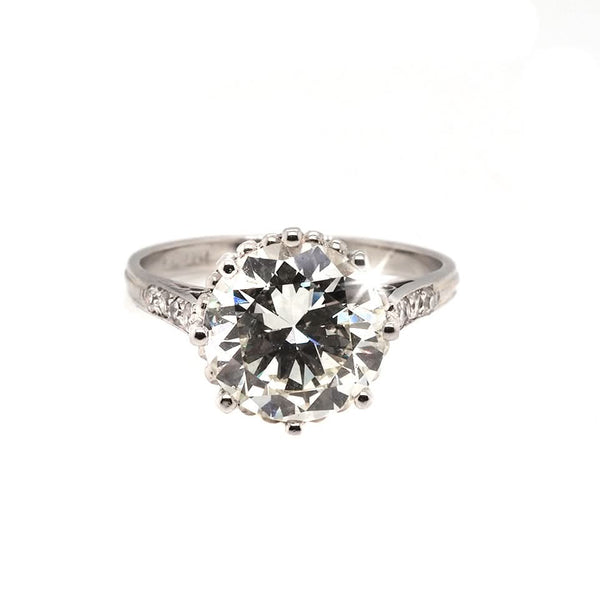 A single stone diamond engagement ring with diamond set shoulders mounted in platinum