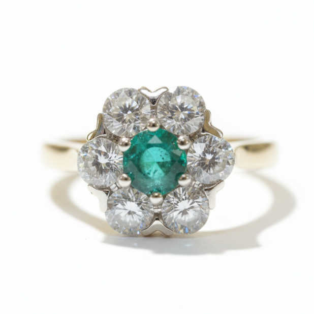 A round emerald and brilliant cut diamond cluster ring in platinum