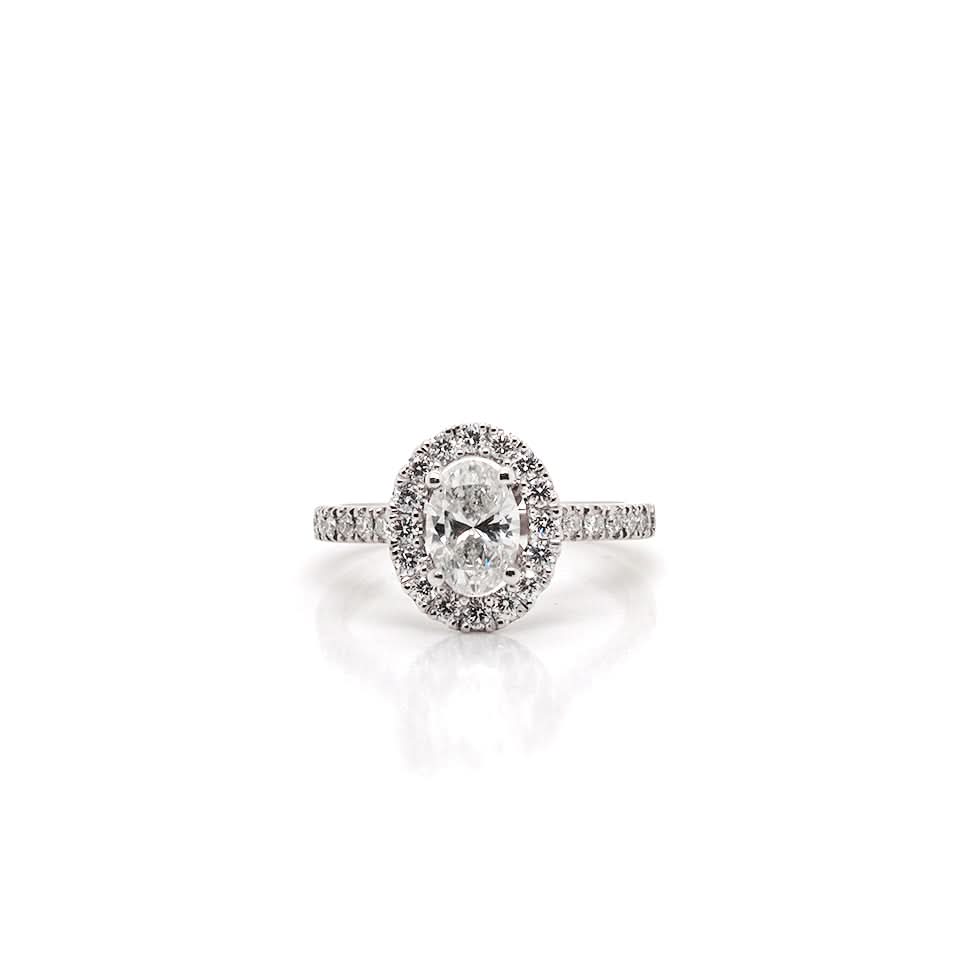 An oval cut diamond ring in platinum with a diamond surround and diamond shoulders