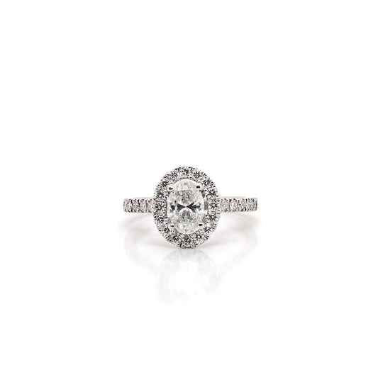 An oval cut diamond ring in platinum with a diamond surround and diamond shoulders