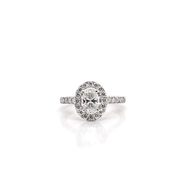 An oval cut diamond ring in platinum with a diamond surround and diamond shoulders