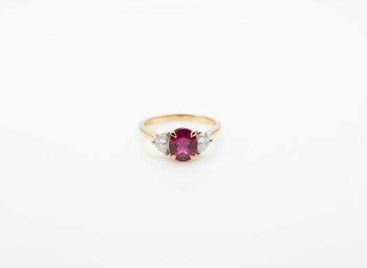 A yellow gold three stone ring with an oval ruby and two fancy cut diamonds