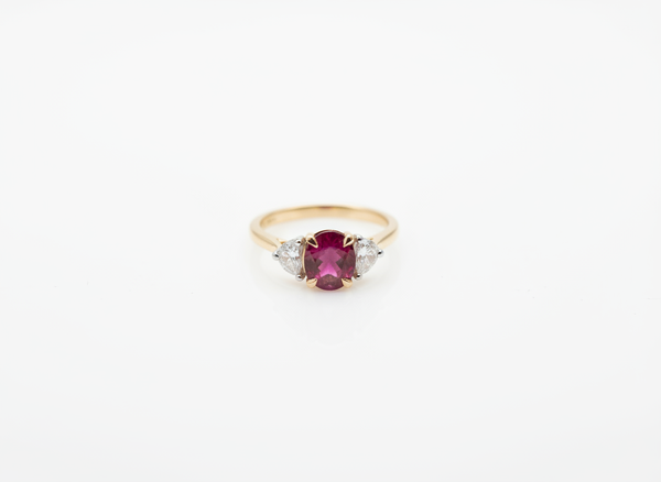 A yellow gold three stone ring with an oval ruby and two fancy cut diamonds
