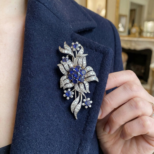 A flower spray brooch set with sapphires and diamonds, set in palladium, modelled on a black jacket