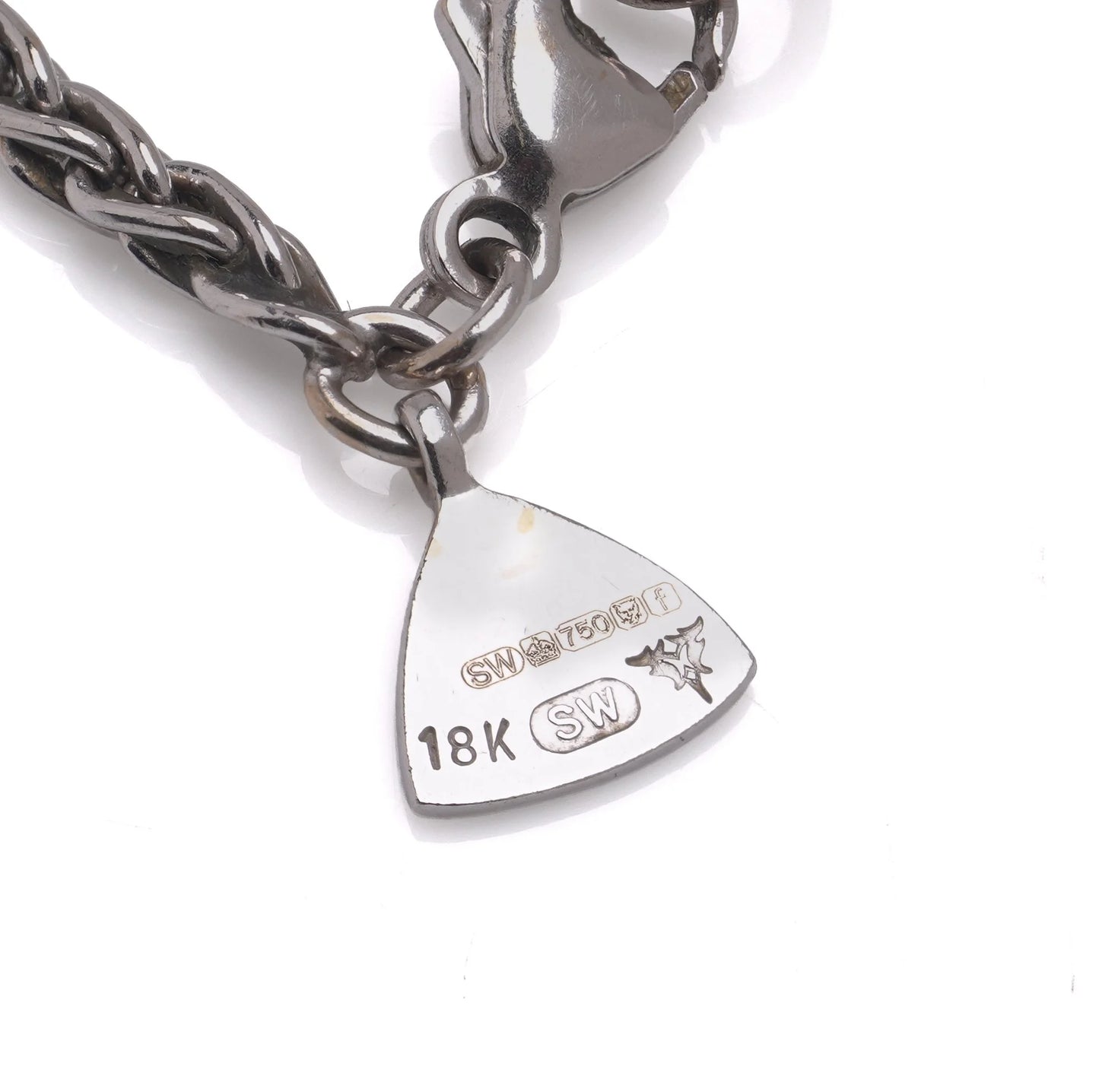 Close-up of a necklace tag stamped 18K, SW, and with an 18 carat gold hallmark