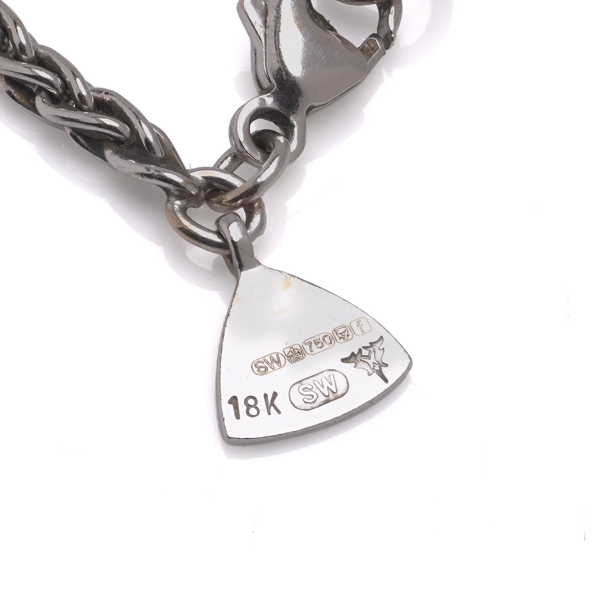 Close-up of a necklace tag stamped 18K, SW, and with an 18 carat gold hallmark