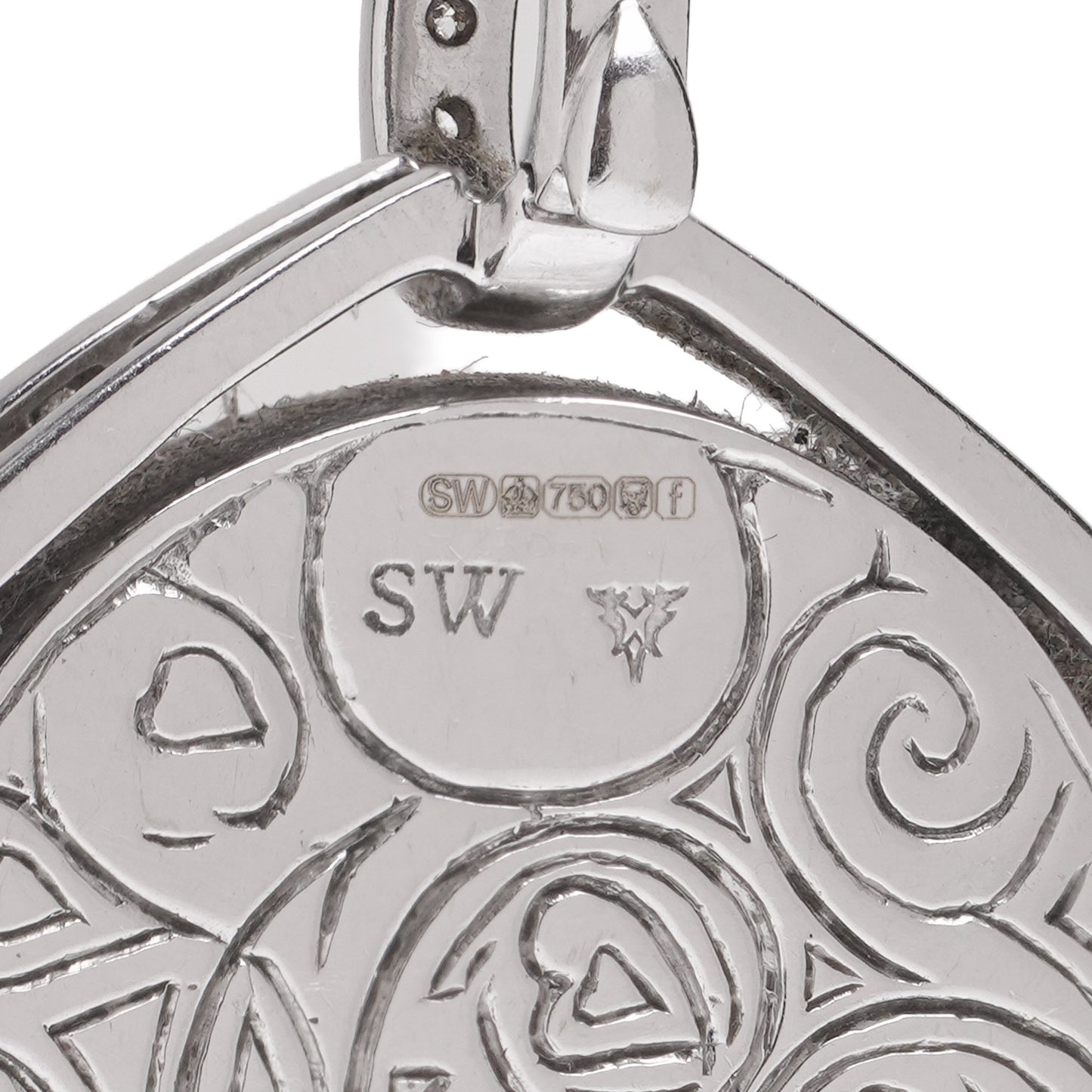 Close-up of an 18 carat gold hallmark and SW stamp on an engraved pendant