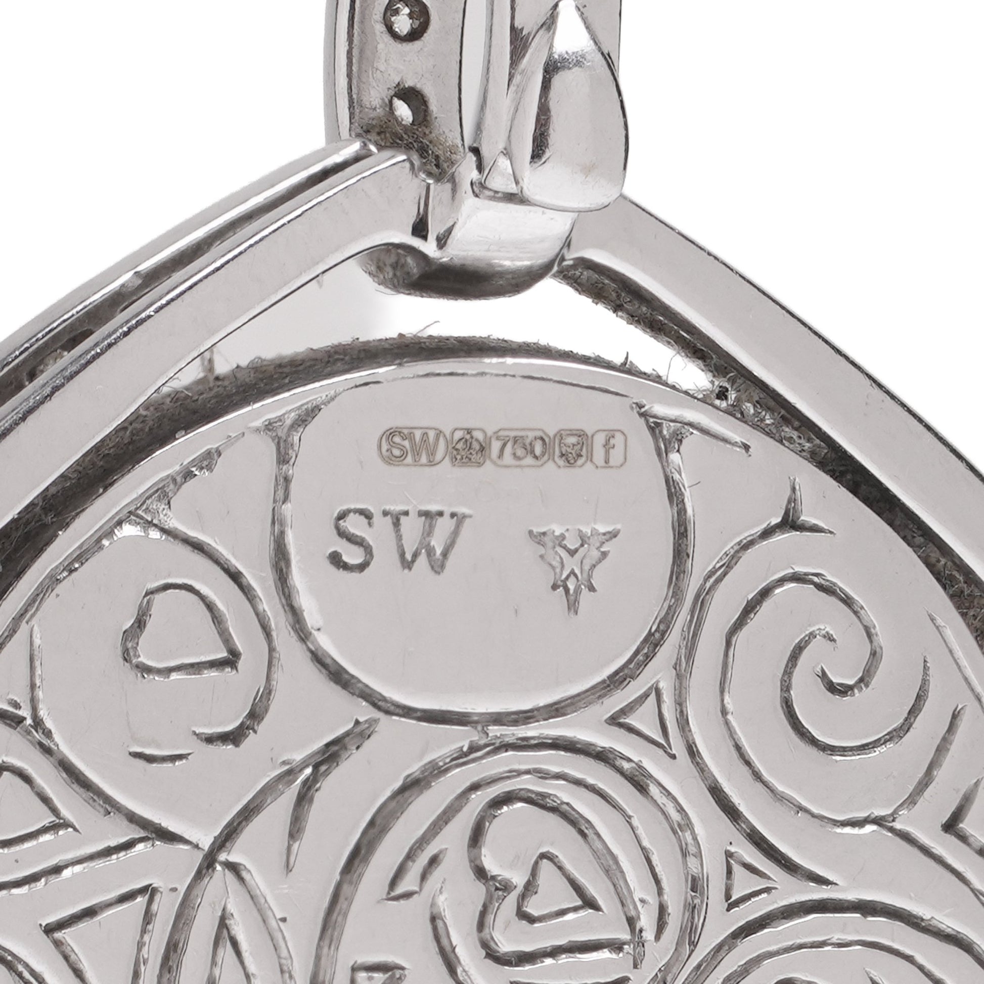 Close-up of an 18 carat gold hallmark and SW stamp on an engraved pendant