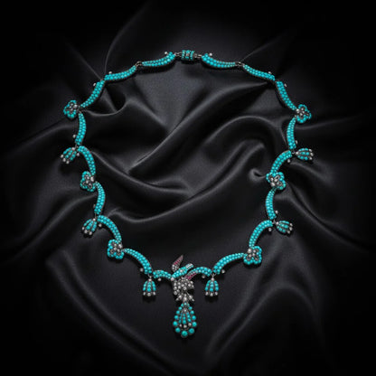 An antique turquoise bead and pearl fancy necklace with a bird motif, on a black satin material