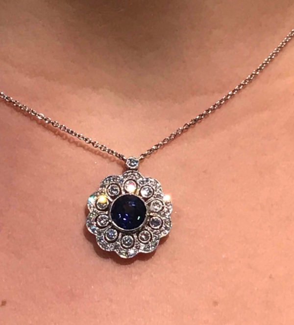 Edwardian style sapphire and diamond cluster pendant, the fine work of the open work pendant set with a sapphire of 2.08 carats to a millegrain setting with a diamond surround.