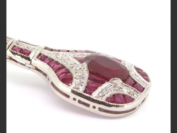Central oval ruby encompassed by baguette cut rubies, detailed with round cut diamonds