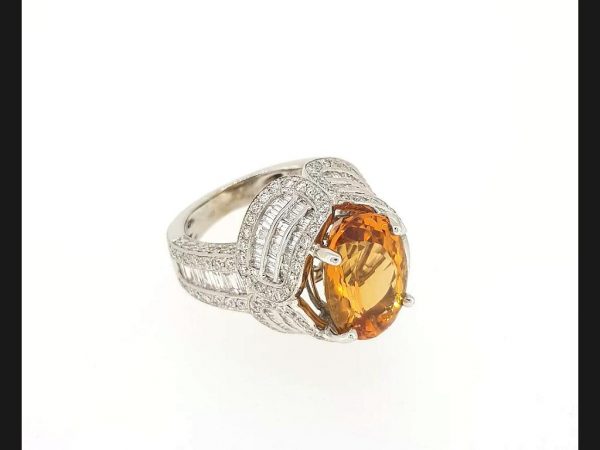 Brazilian Topaz and Diamond Dress Ring; Oval cut Brazilian topaz in four claw setting, surrounded by an intricate design of round and baguette cut diamonds
