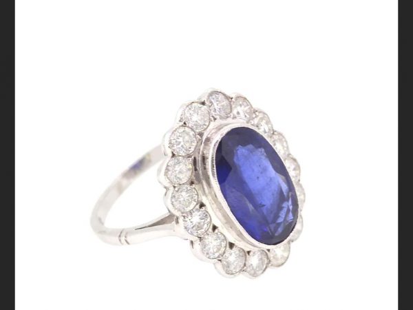 Vintage Sapphire and Diamond Cluster Ring; Central oval cut sapphire surrounded by round cut diamonds, 18ct white gold