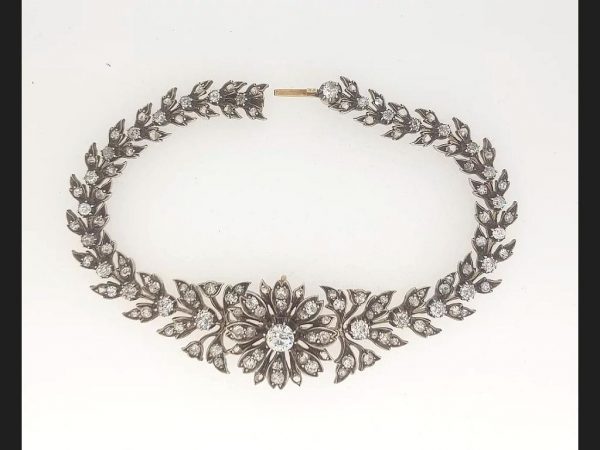 An antique diamond bracelet set with old cut diamonds in an intricate floral pattern continuous throughout the entire bracelet setting, in silver and gold