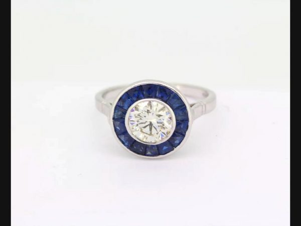 Vintage Art Deco Style Sapphire and Diamond Calibre Set Ring; round cut 1.21ct diamond encircled by sapphires.