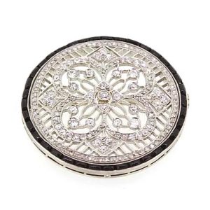 Art Deco Diamond Onyx and Platinum Circular Brooch; featuring a diamond-set floral and geometric design, surrounded by a halo of calibre-cut onyx.