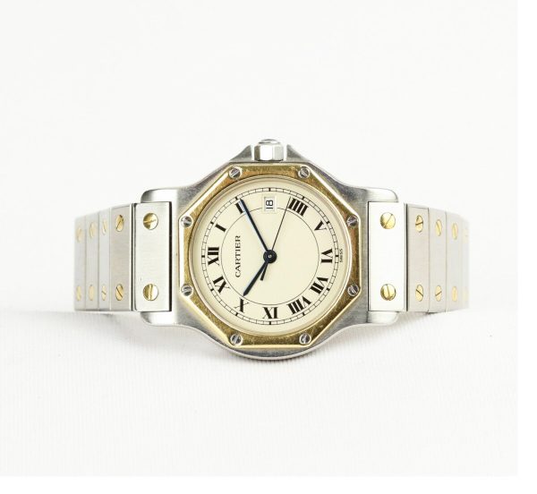 Cartier Santos Stainless Steel and Gold Bracelet Watch; 29mm steel case, white dial, Roman numerals, date aperture at 3, blue gem set crown, gold bezel.