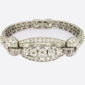 Vintage Diamond and Platinum Panel Bracelet; five graduated round-cut diamonds surrounded by baguette and circular-cut diamonds, 16.50 carat total